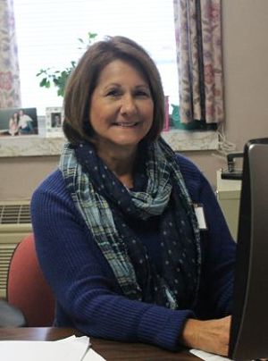 Picture of a female Social Services staff member sitting at her desk smiling.