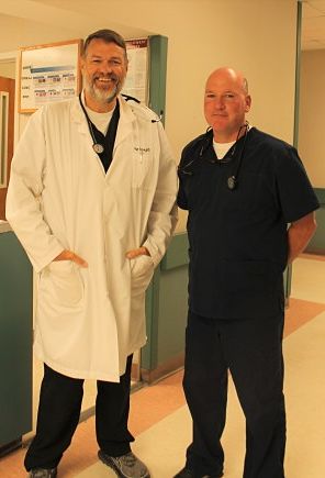 Picture of Dr. Armstrong and Dr. Bair standing in a hospital hallway wearing scrubs and doctor coat.