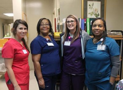 Picture of four nurses standing in hospital hallway wearing scrubs.